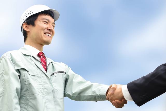 作業服の男性が握手をしています。